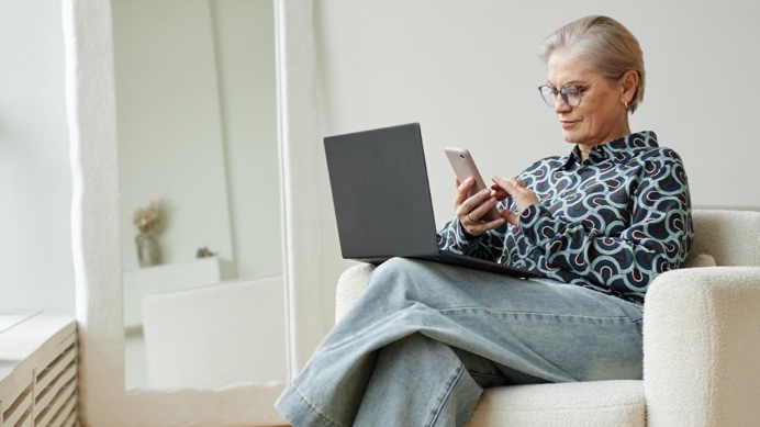 Older woman on mobile phone sat on a sofa