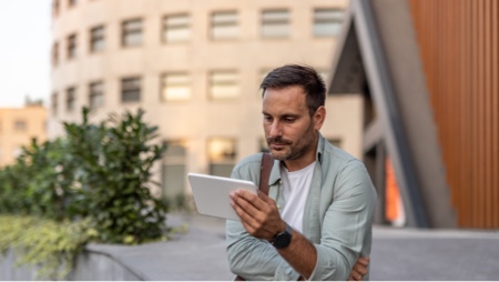 Middle-aged man outside of buidling with touchscreen tablet